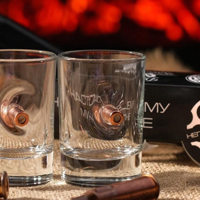 Во второй стопке. Рюмка с пулей. Граненый стакан на столе. Граненый стакан. Картон.